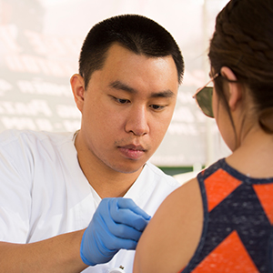 health professional adminstering shot to patient's left arm