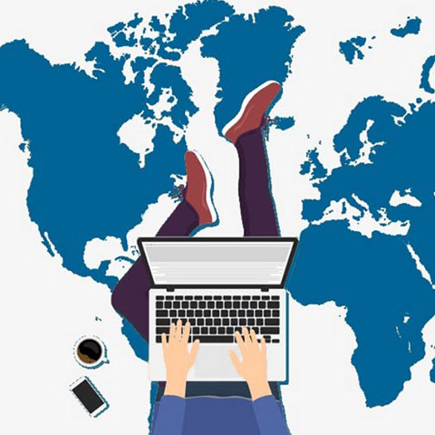 person sitting on floor using their laptop with world map underneath them along with coffee cup and phone sitting next to their left leg